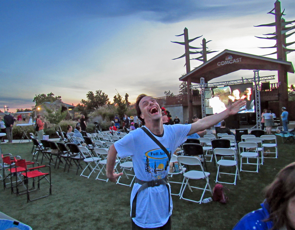 Full Access client smiling brightly for the camera at the Sprout Film Festival, with the large screen displaying films in the background.